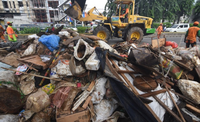 Petugas kebersihan tengah mengumpulkan sampah sisa banjir dari wilayah permukiman Bidara Cina, Jakarta